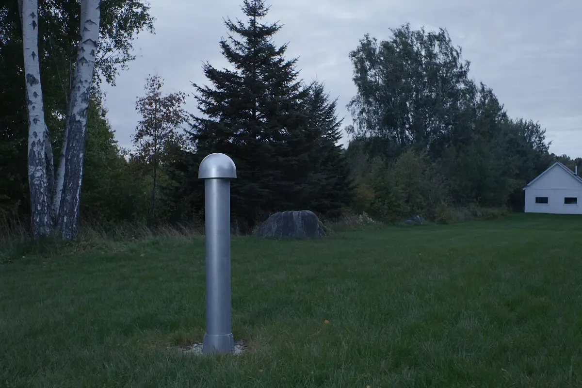 Steel well casing in a Maine yard with birch and spruce trees